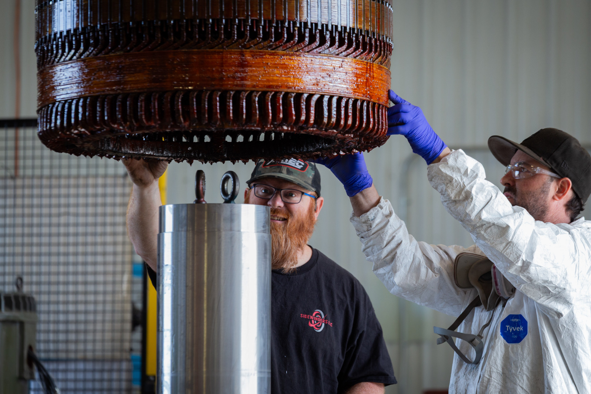 Sidewinders technicians guiding a freshly varnished stator core into place